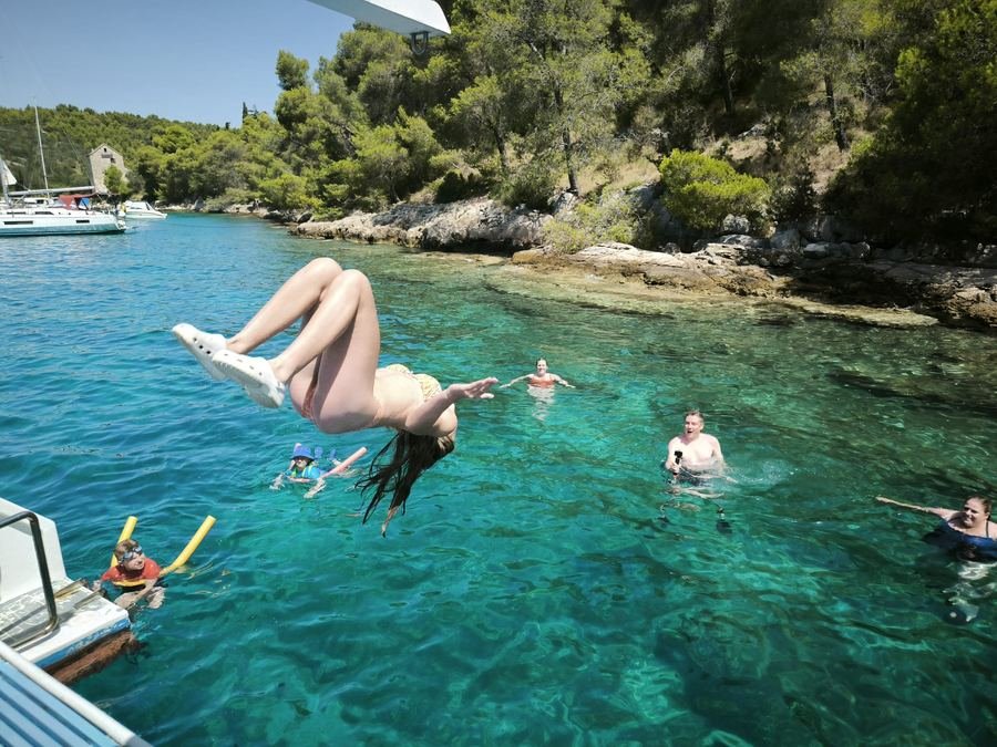 A guest jumping off the catamaran into clear water during a swim stop