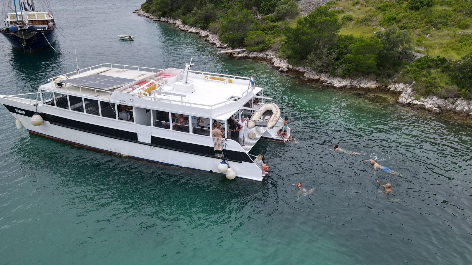 The catamaran Mariano anchored in a turquoise Adriatic bay while guests swim alongside
