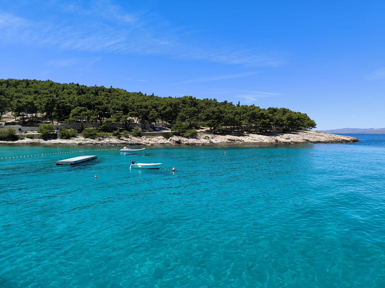A quiet turquoise bay on Šolta with a floating pontoon and moored boats